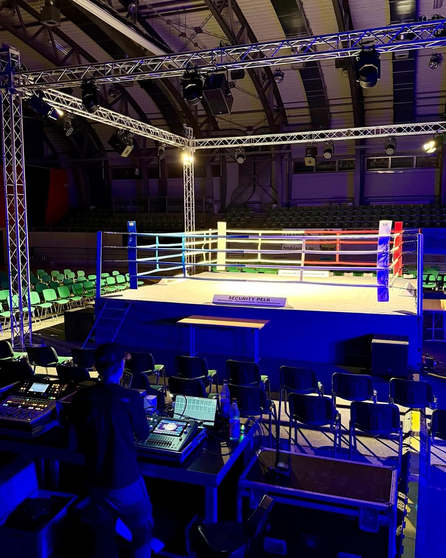 Fight Night Cottbus 2025: Boxring unter einem Traversen-Rig mit Scheinwerfern, vorn der Technikplatz mit zwei digitalen Mischpulten